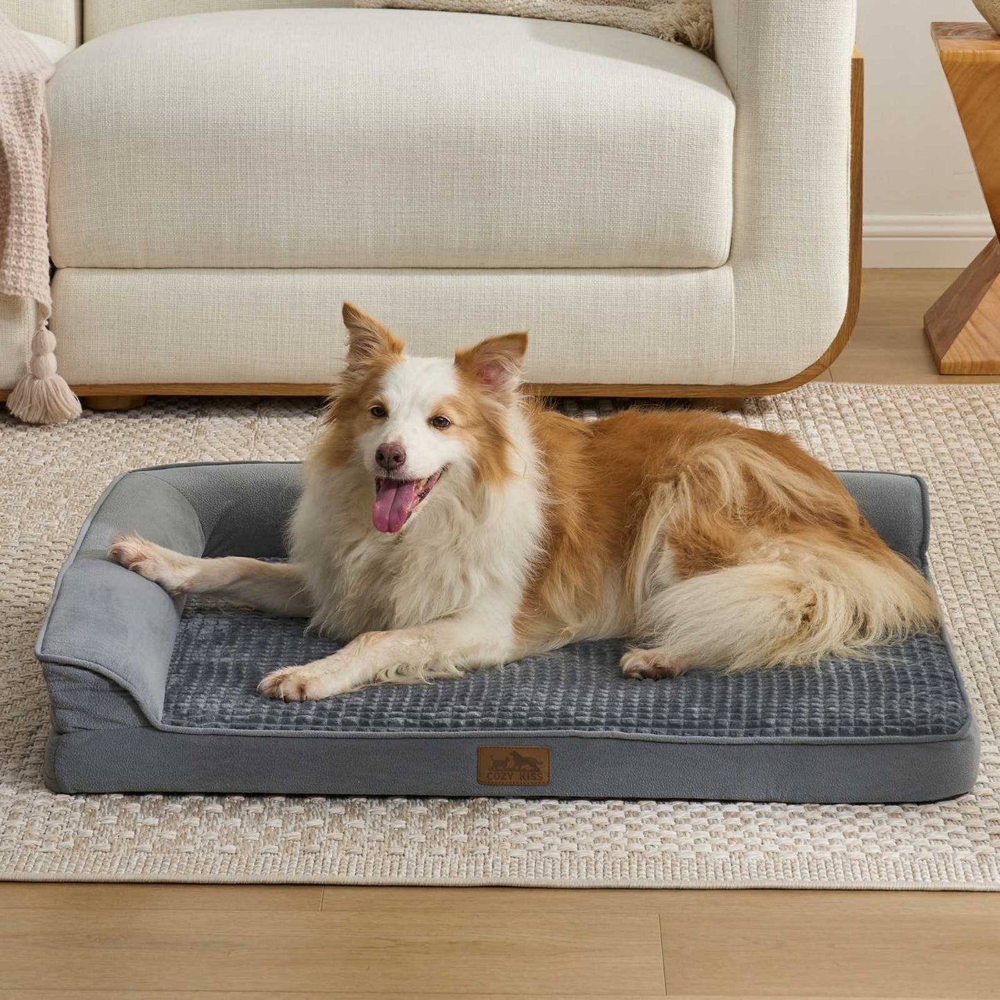 Cozy Kiss All Seasons L-shaped scratch-resistant dog bed in grey with a dog lounging in a bright living room#color_Grey