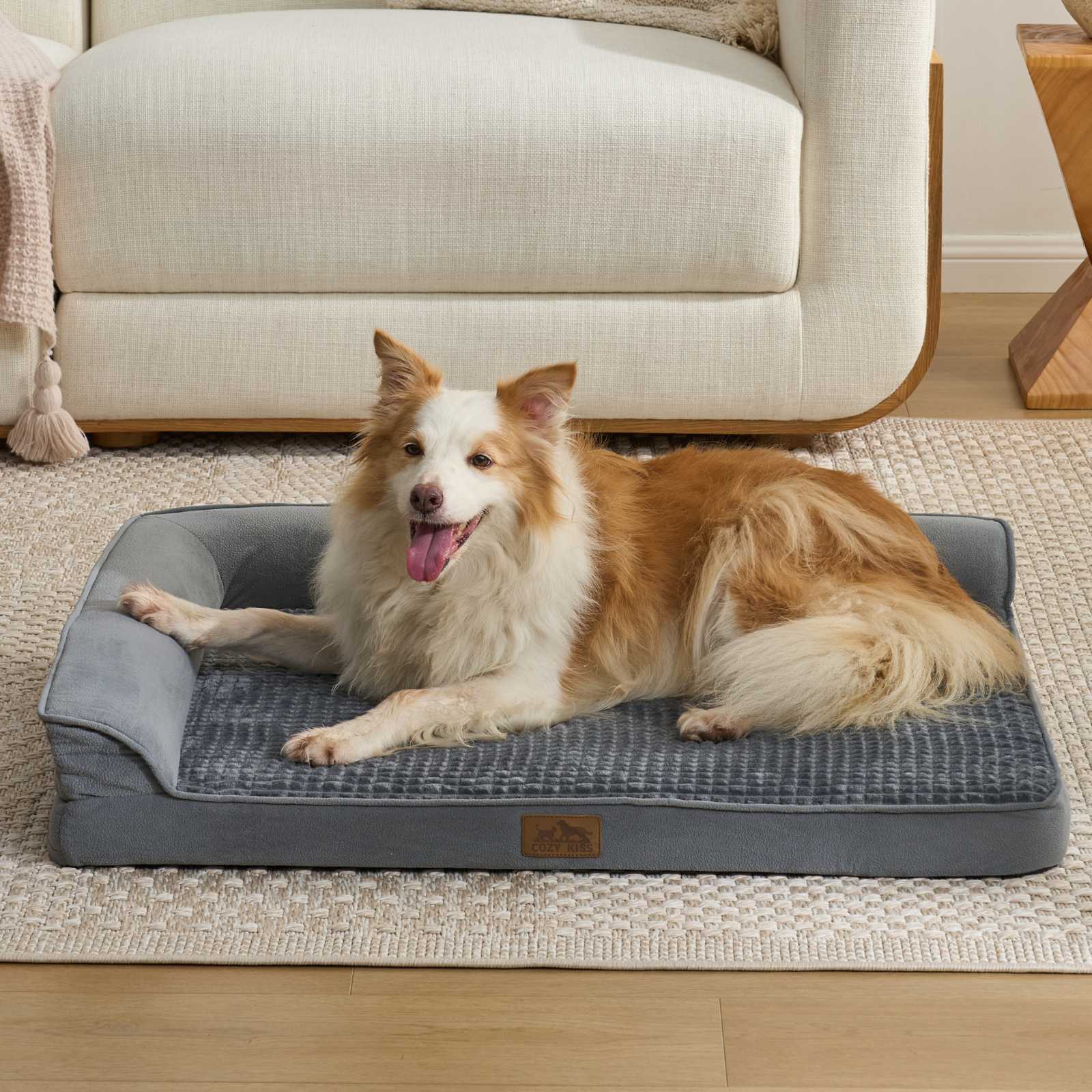 Cozy Kiss All Seasons L-shaped scratch-resistant dog bed in grey with a dog lounging in a bright living room#color_Grey