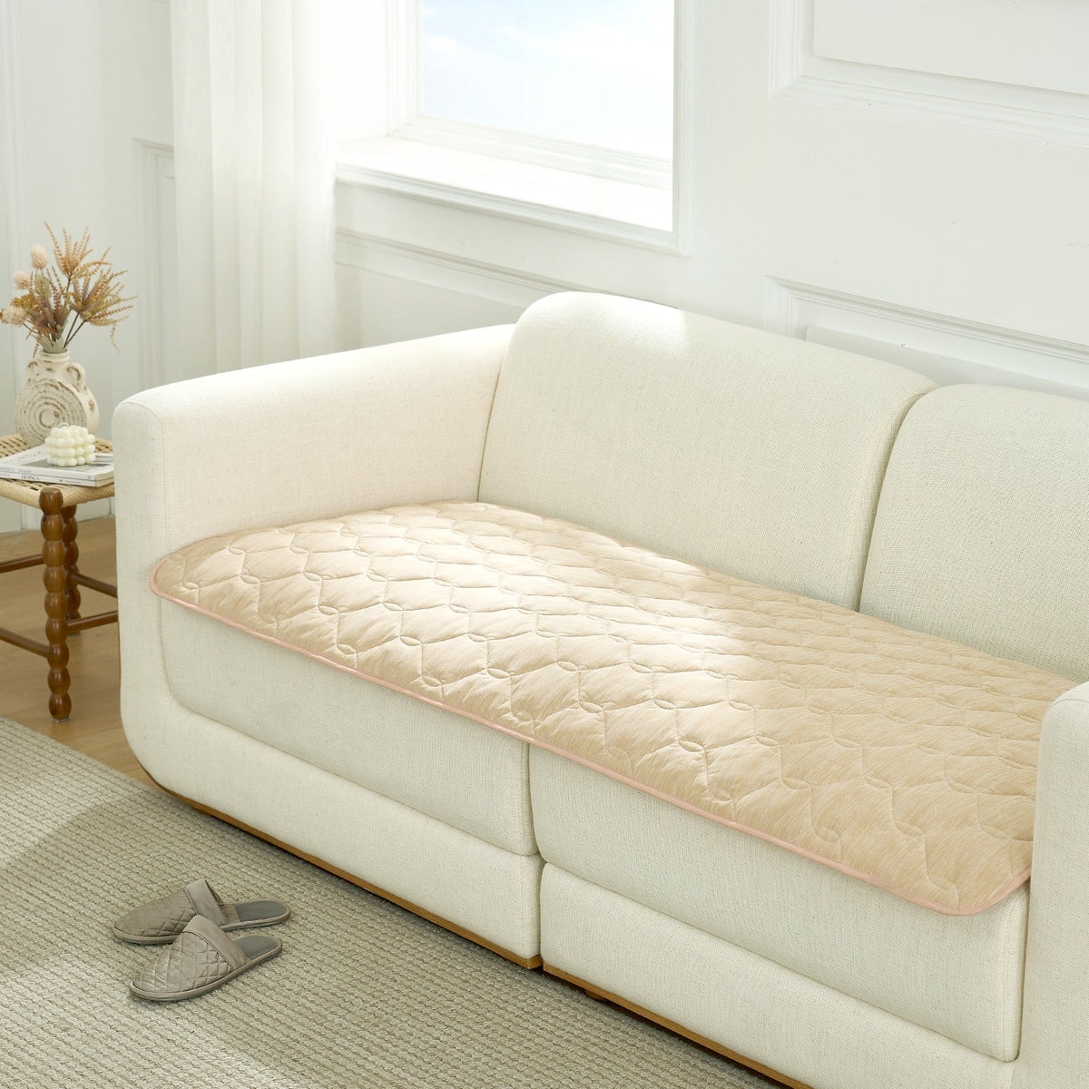 Beige couch cover on a white sofa in a living room setting.