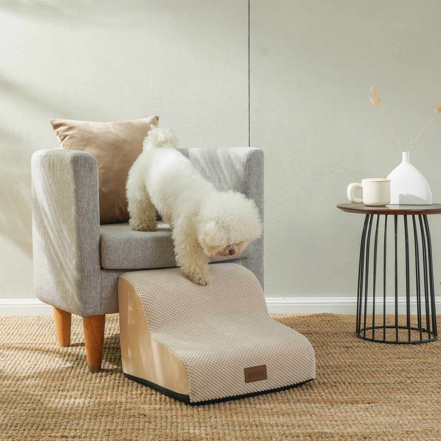 Cozy Kiss 2-Step Joint-Friendly Curved Pet Stairs with washable cover beside armchair helping small dog safely climb down #color_Beige